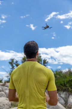 Man piloting a drone outdoors under blue sky and clouds