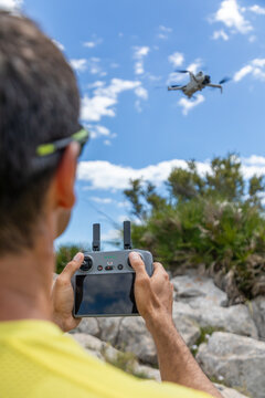 Drone pilot controlling quadcopter outdoors in rocky landscape