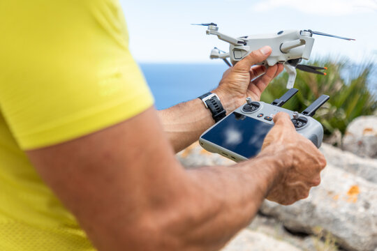 Drone pilot holding quadcopter and remote by the sea