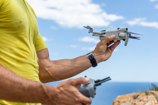 Man holding drone and remote controller by sea cliff