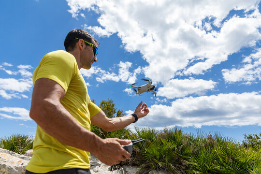Man operating a drone outdoors under blue sky and clouds