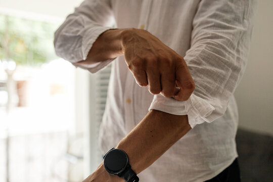 Close up of mature man adjusting shirt sleeves before leaving home showing everyday fashion details and natural lifestyle.
