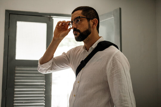 Authentic lifestyle moment of a man dressing at home before leaving, emphasizing personal style and preparation.
