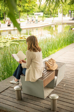 Mature blond haired woman reading a book in a peaceful city park