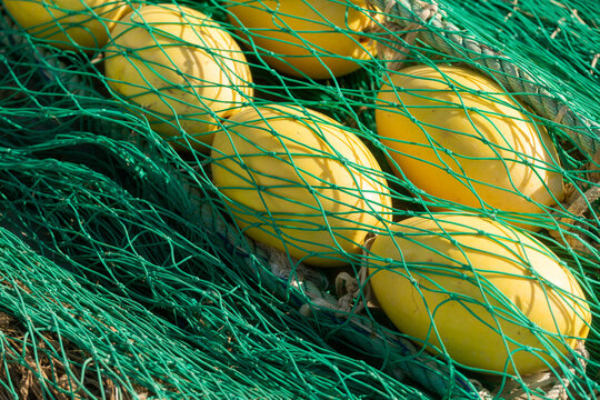 Yellow fishing floats caught in green net close-up texture