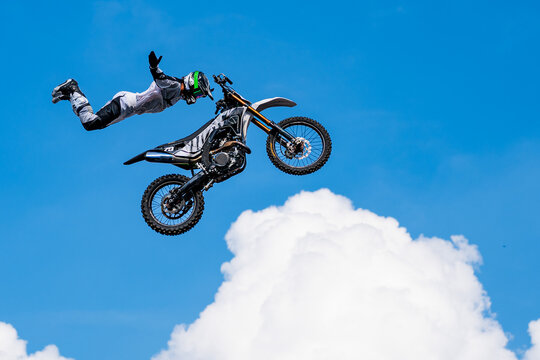 Motocross rider performing spectacular freestyle jump high in the air against blue sky, showcasing extreme sport, skill and adrenaline-filled action