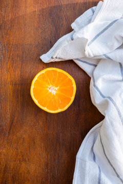Fresh orange half on wooden surface with cloth