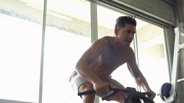 Shirtless muscular athletic man doing heavy weight lifting on t bar row machine at gym. Fit male building back muscle with intense strength training workout for healthy body
