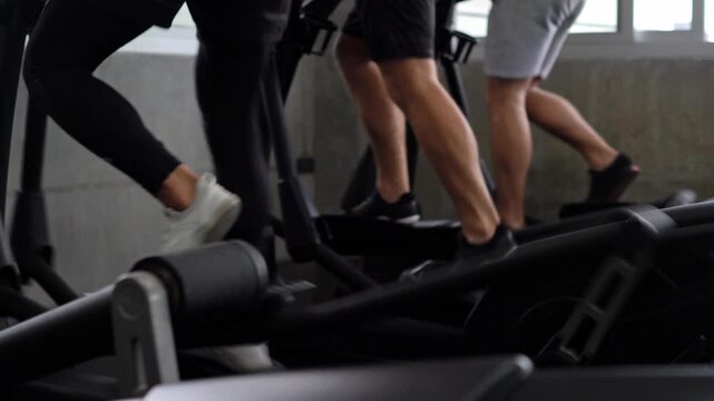 Active human leg running on elliptical trainer machine at gym. Group of fit person doing cardio exercise for healthy lifestyle.
