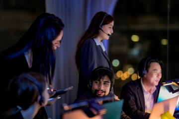 Fototapeta premium Team of consultants checking a smartphone lit by its screen in a dimly lit software studio, solving a problem together, in a scene about innovation and focused late-night mood.
