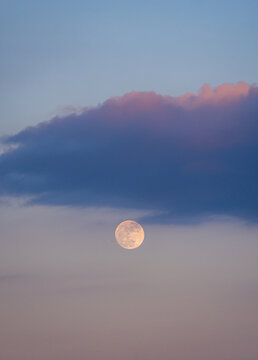 Full moon under blue cloud in pastel twilight sky
