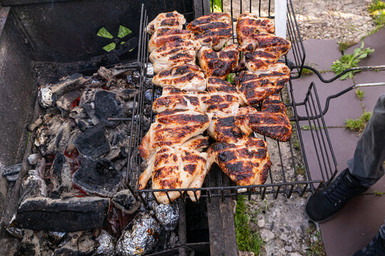 Grilled chicken on barbecue rack over hot charcoal outdoors