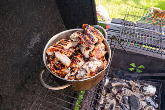Grilled chicken pieces in pot on barbecue grill in summer
