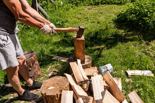 Man chopping firewood with an axe in sunny backyard