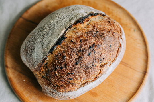 Rustic artisan sourdough loaf on wooden board, top view