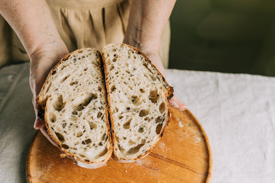 Hands holding sliced rustic artisan bread with airy crumb