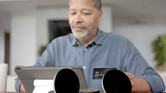 Man holding credit card near tablet, initiating animated coins falling and stacking for finance app