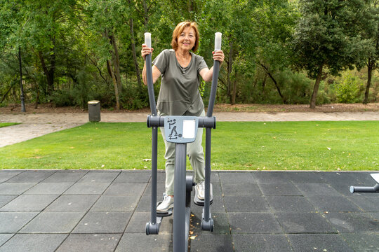 Senior woman exercising on outdoor fitness machine in park