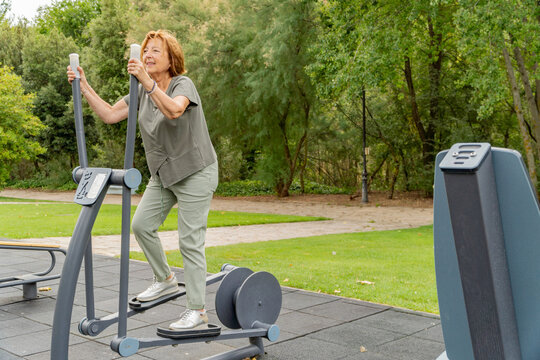Senior woman exercising outdoors on park fitness machine
