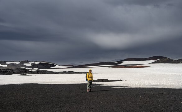 Hikers in snow-covered volcanic landscape with volcanic sand and petrified lava, crater of Askja volcano, Icelandic highlands, Iceland