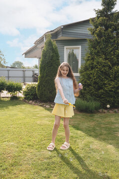 Girl blowing bubbles in backyard during sunny summer play