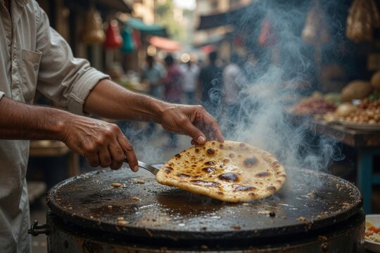 Street vendor cooking traditional indian flatbread on a hot pan in a bustling marketplace, fresh naan bread