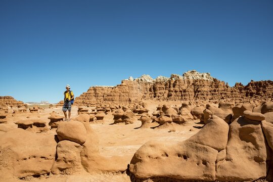 Tourist, young man likes Hodoo, eroded Hoodoos, rock formation of Entrada sandstone, Goblin Valley State Park, San Rafael Reef, Utah, southwest, USA