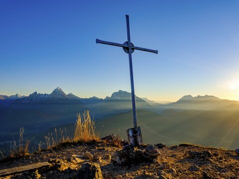 Rauher Kopf summit cross in the evening light, in the background the Berchtesgaden Alps, Sch&ouml;nfeldspitze, Watzmann, Hochkalter and Reiteralpe, Berchtesgaden National Park, Bischofswiesen, Berchtesgadener Land, Upper Bavaria, Bavaria, Germany