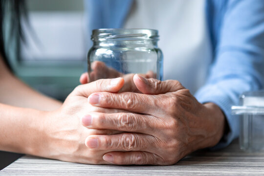 Mother and daughter hands holding jar in kitchen at home