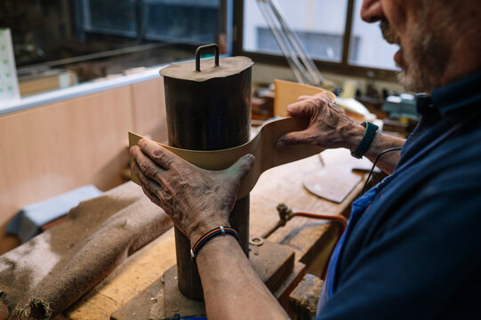 Skilled craftsman shaping wood for a guitar in workshop
