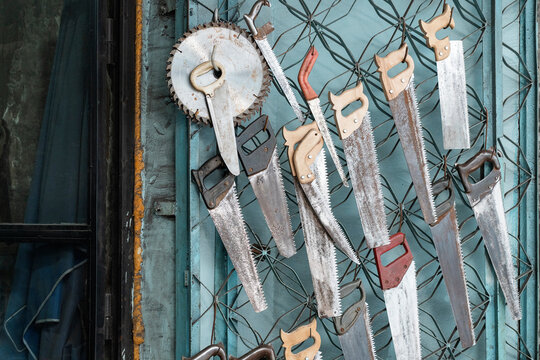 Old hand saw collection hanging on workshop metal wall