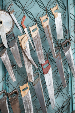 Old hand saw collection hanging on workshop metal wall