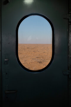 View from inside a train looking at desert through window