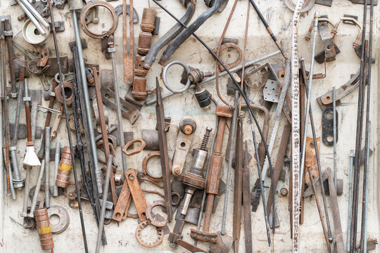 Assorted rusty metal tools and parts hanging on workshop wall