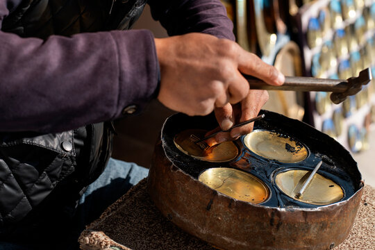 Street artisan casting metal pieces in a small workshop