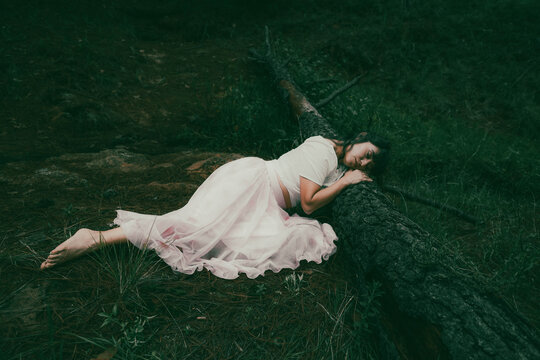 Lost in a dreamy land. Beautiful woman in mystical stream. Romantic woman into a stream. Woman dreaming in Woods.