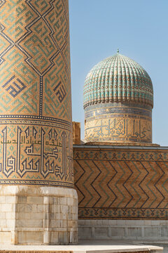 Ancient Bukhara mosaic minaret and turquoise dome facade