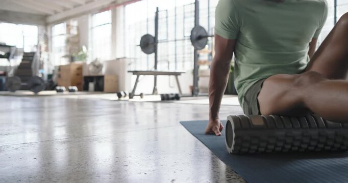 Man seated on blue mat rolling foam roller on thigh for relief rising walking, copy space