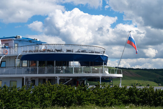 Passenger river ship with Russian flag under dramatic sky