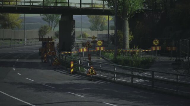 Empty urban road with barriers underpass, dusk light, construction cones and metal fencing, lane closure markers with reflective tape, quiet atmosphere, no