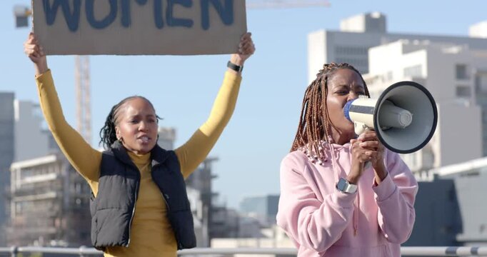 African women protesting on roof right woman raising megaphone calling holding WOMEN sign hoodie