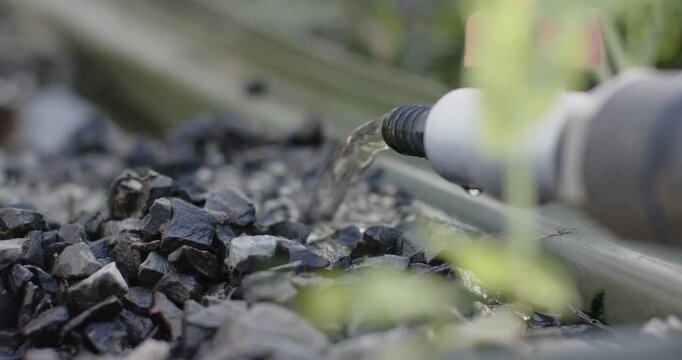 Water pressure is forcing clear stream from pipe nozzle onto crushed stones for drainage