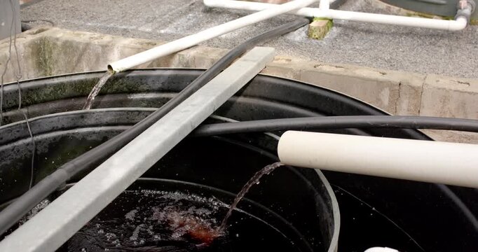 Large black tank is receiving steady streams from PVC spouts releasing water for recycling