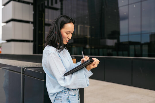 Asian businesswoman using tablet outdoors