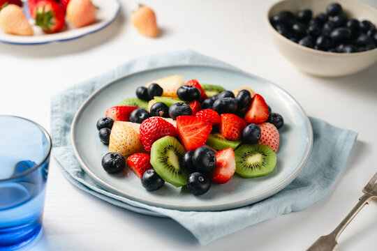 Fresh fruit salad in a plate, kiwi slices, strawberries and blueberries. Healthy food, sweet dessert, top view