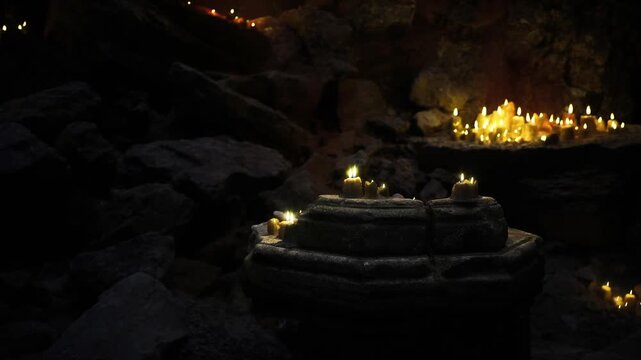 Practical candle effects on cavern set, cinematic lighting and props creating moody atmosphere for film production with crewready ambience and textured rock