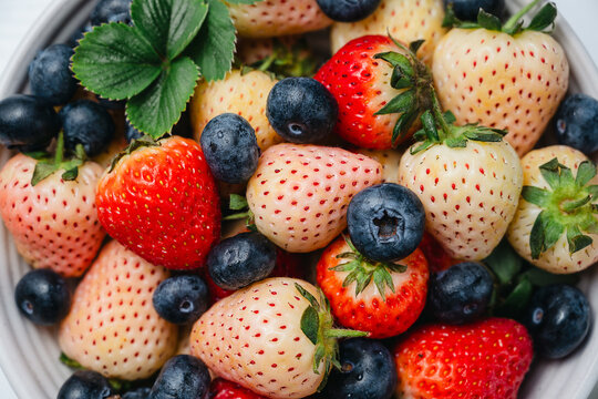 Fresh fruit salad in a plate, kiwi slices, strawberries and blueberries. Healthy food, sweet dessert, top view
