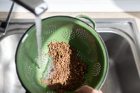 Rinsing Dry Lentils Under Running Water in Kitchen Sink