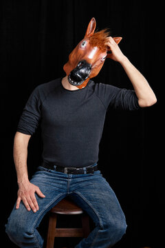 Man in horse mask scratching head confused humorous surreal studio portrait