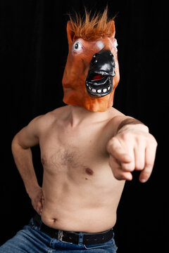 Shirtless man in horse mask pointing at camera humorous surreal studio portrait